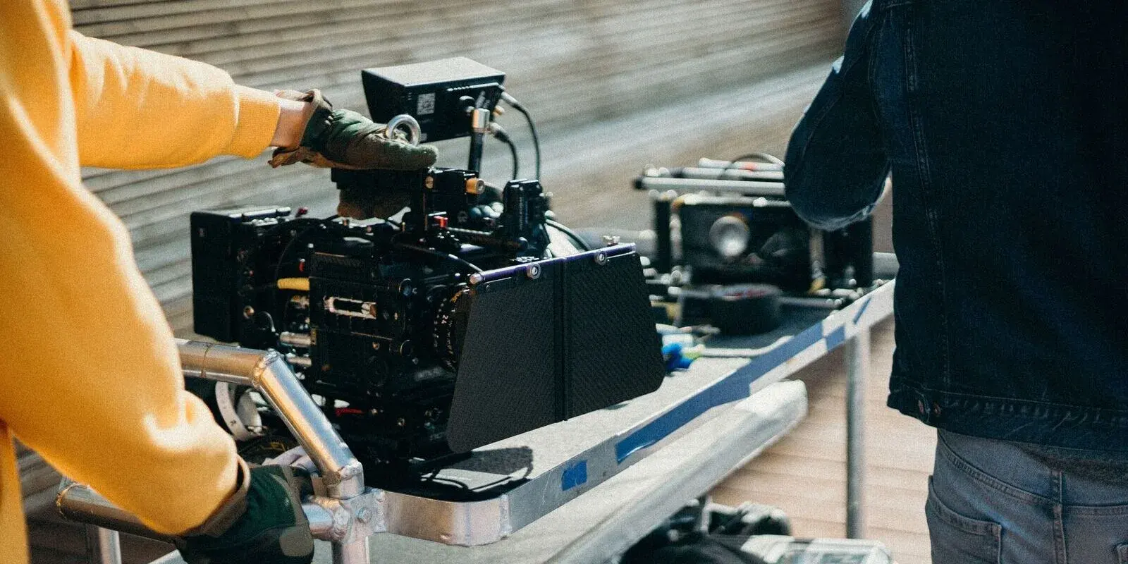 A film crew setting up a cinema camera on a rig at an outdoor location shoot