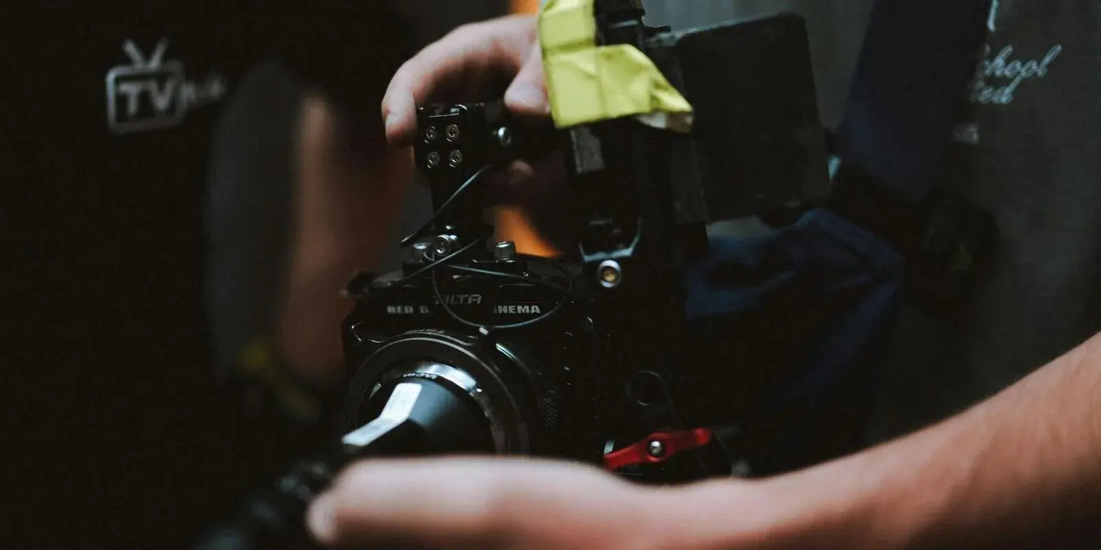Hands adjusting a cinema camera rig on a darkened production set