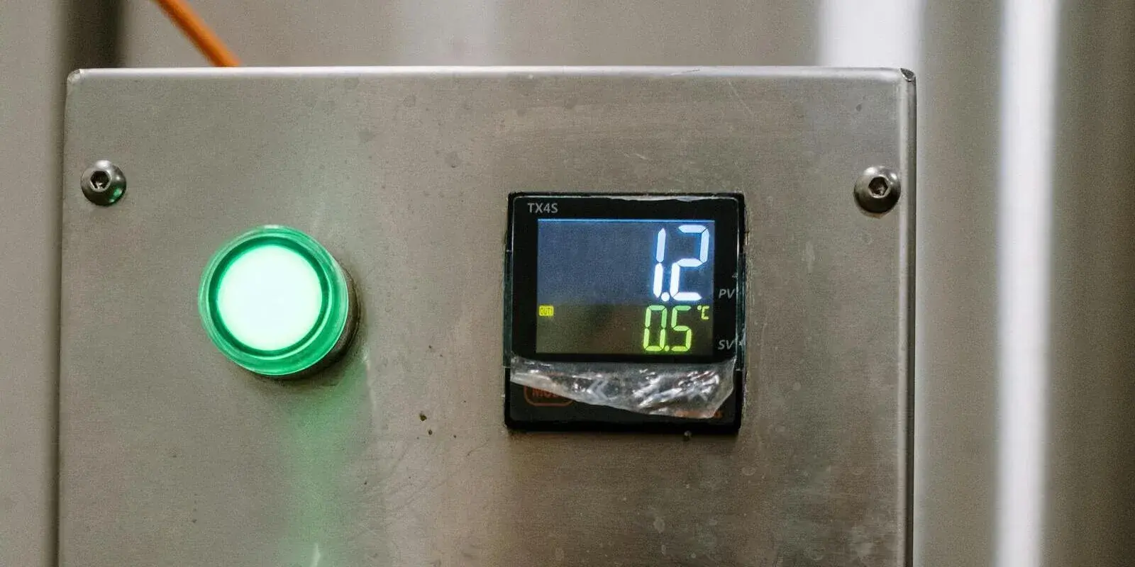 A digital temperature controller on a stainless cold-storage unit showing a low set-point