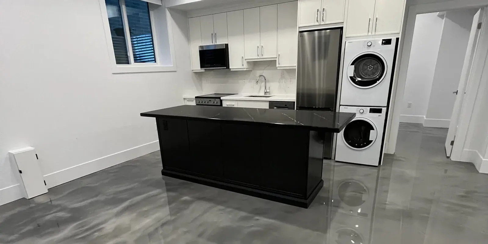 A renovated suite with a finished white kitchen, stainless appliances, and a glossy epoxy floor
