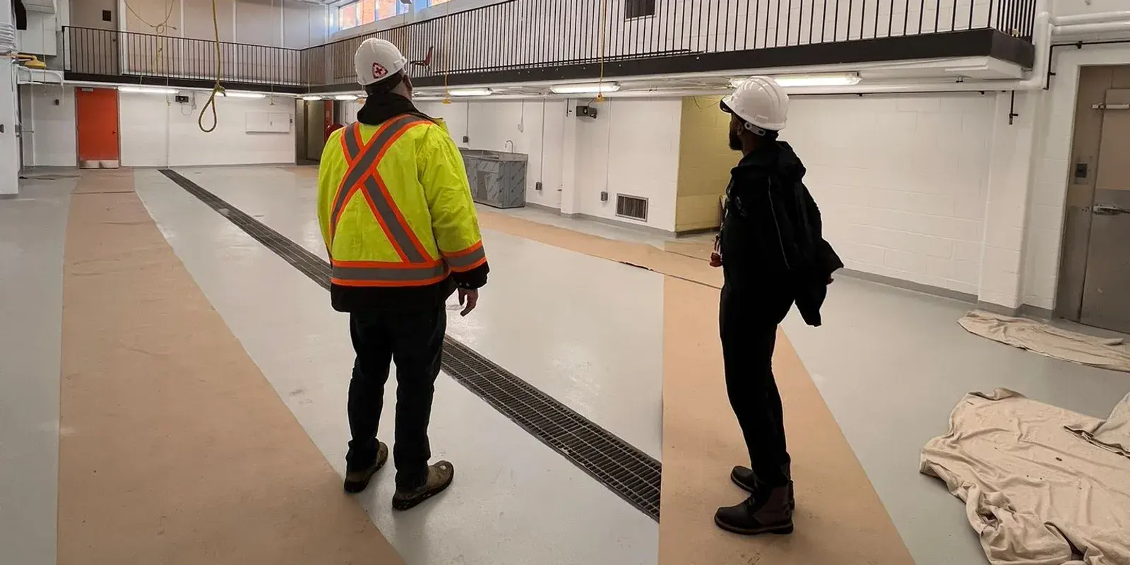 Two crew members in hi-vis inspecting a large finished commercial space before handover