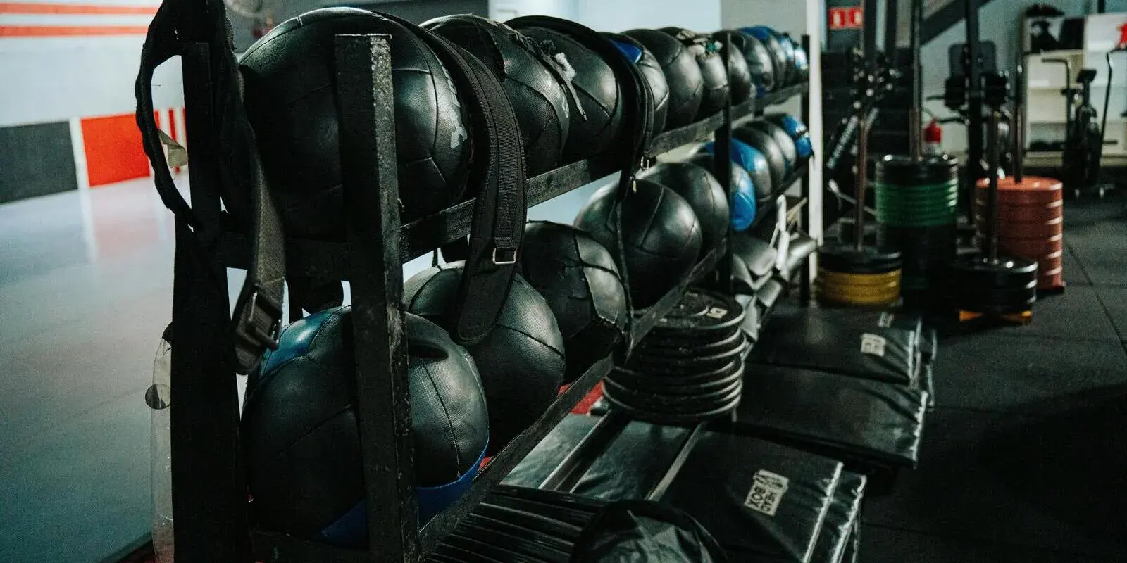 A functional-training rack of medicine balls, weightlifting belts, and bumper plates