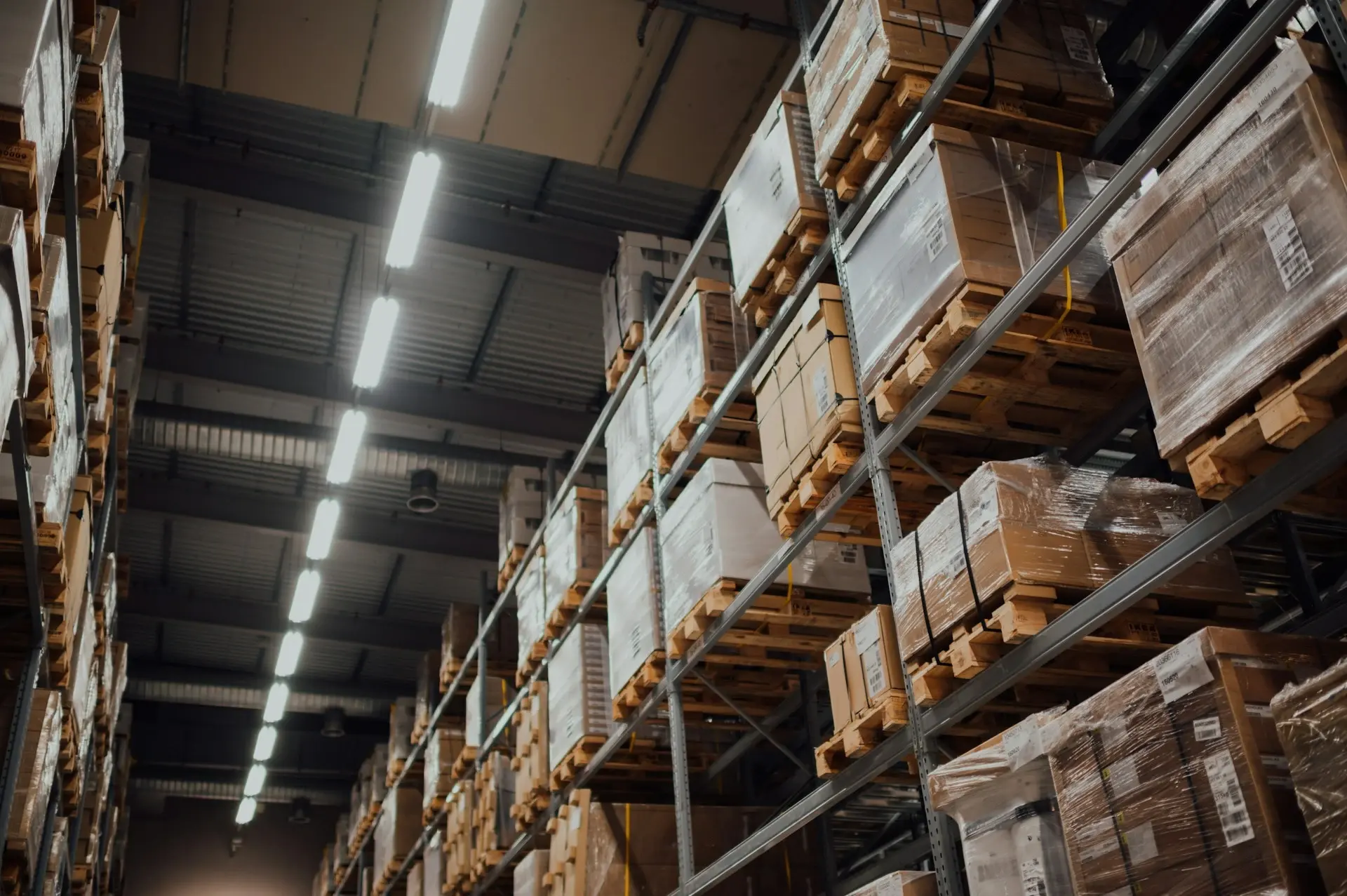 Tall warehouse pallet racking stacked with boxed inventory under industrial lighting