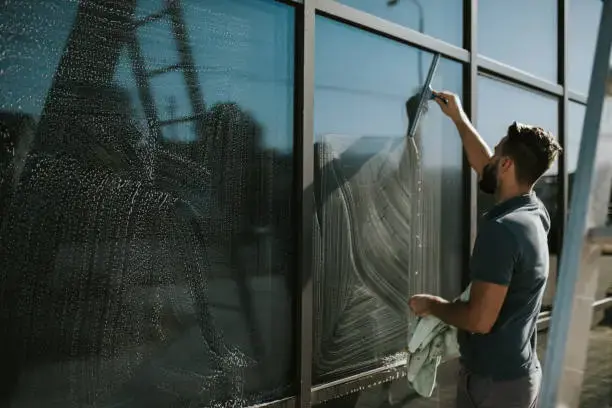 A window cleaner using a squeegee to clean a large commercial glass panel